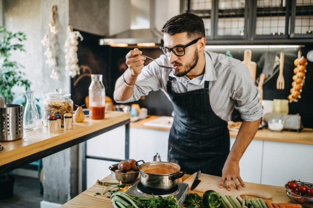 Beginner tasting food while cooking to check seasoning