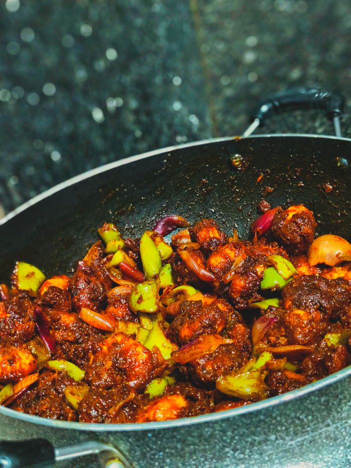 services-03 Spicy chilli prawns cooked with vegetables in a traditional Indian wok, showcasing vibrant flavors and colors.