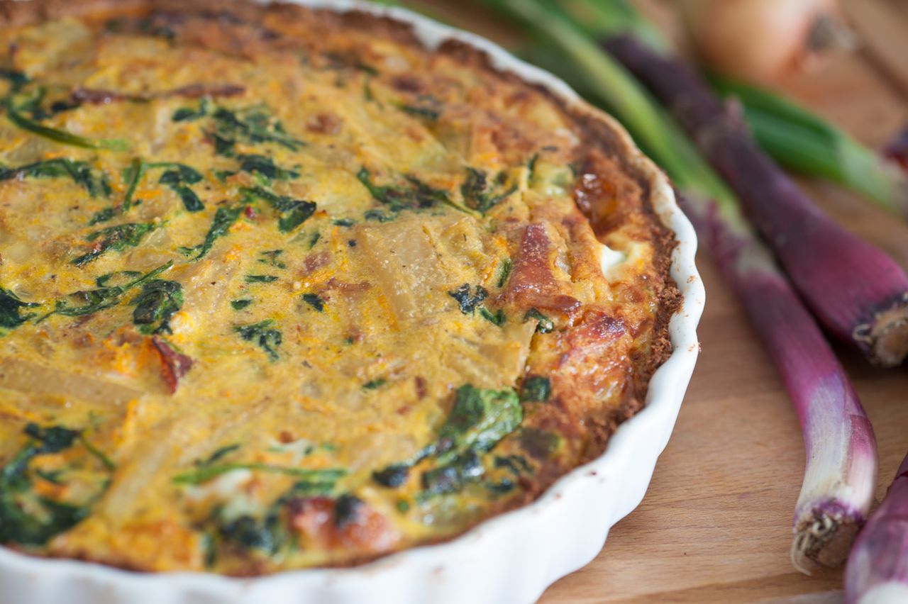 who-we-are Delicious homemade quiche with fresh red onions and spinach, perfect for a tasty meal.