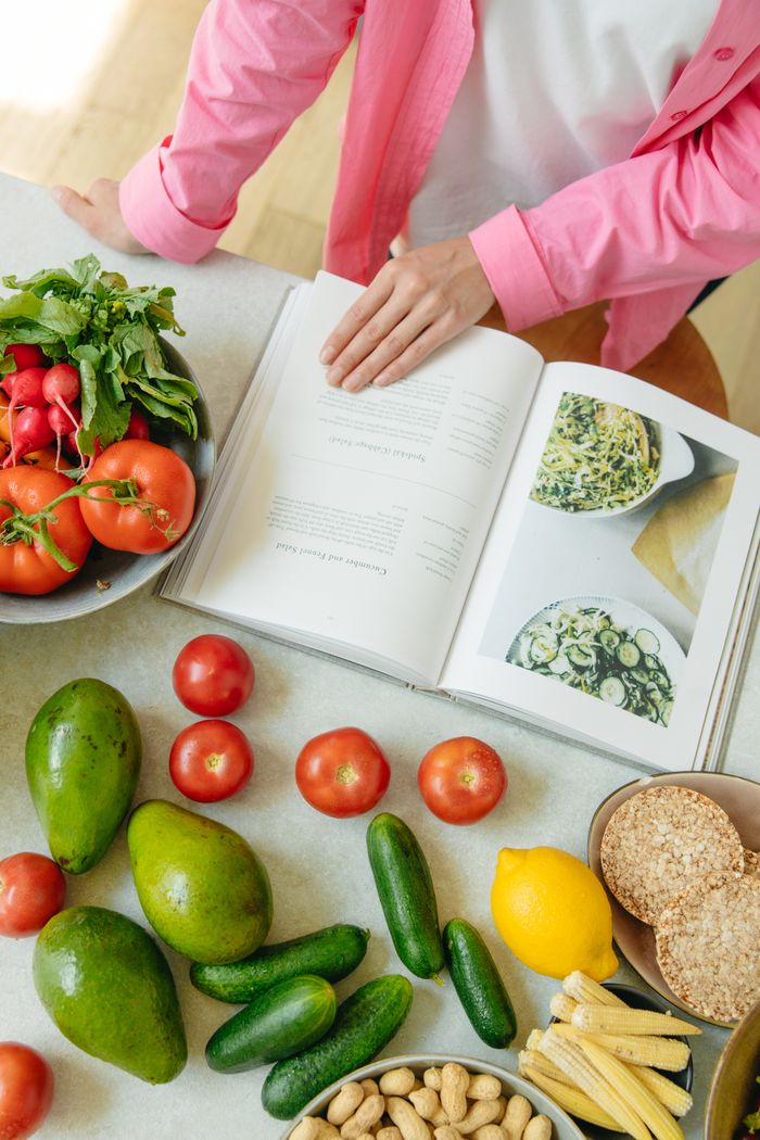 why-choose-us Overhead view of fresh vegetables and an open cookbook on a kitchen counter.